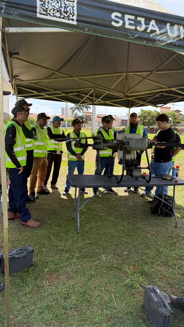 Grupo acompanha demonstração de drone agrícola sob tenda